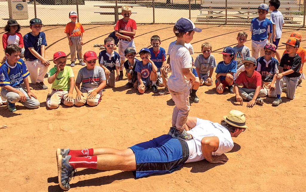 Image of James Lowe on the ground on a baseball field with players watching him.