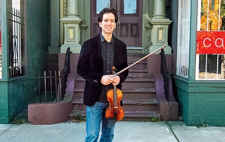 Image of Sebastian Ruth standing on the street with his violin
