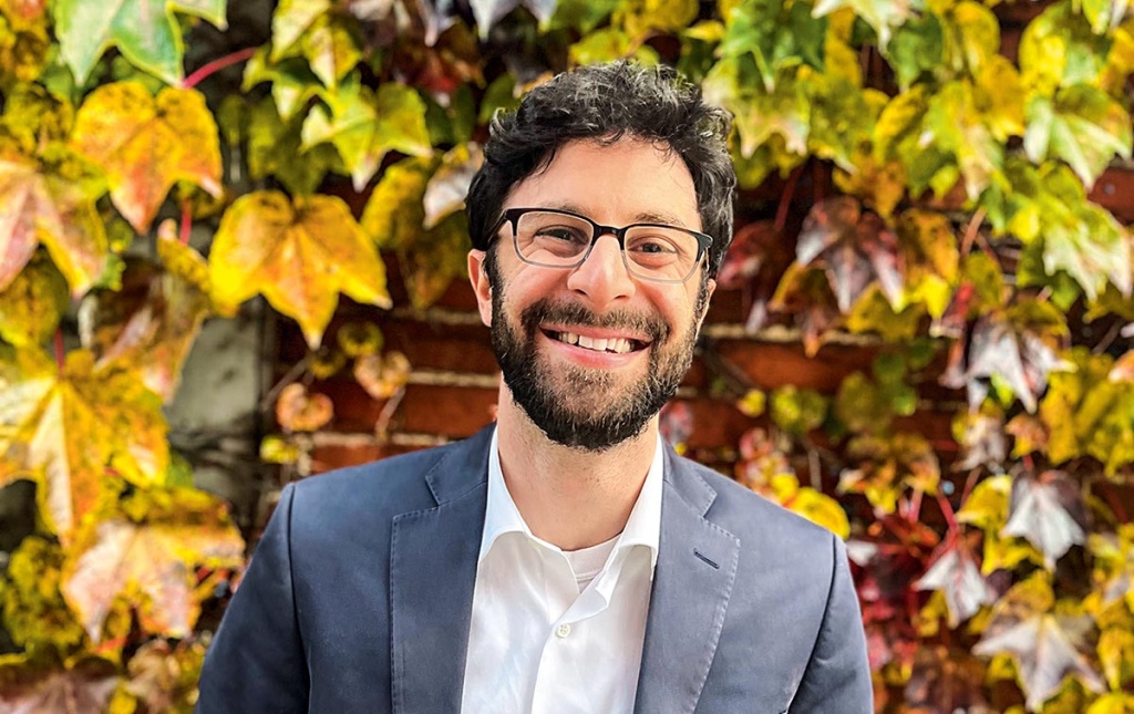 Image of Sidney Kushner in front of a brick wall with fall leaves on it