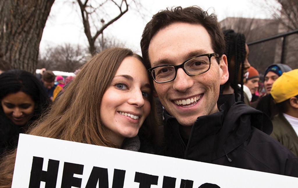 Photo of Kira Ganga Kieffer &rsquo;08 and Aaron Eisman &rsquo;08, at a rally with a sign that says "Healthcare is a Human Right."