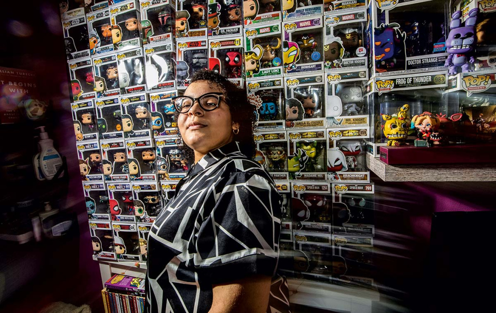 An image of Birana Bisono standing in front of a wall of Funko Pops