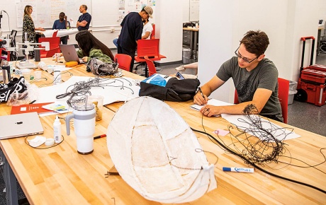 Image of students at a large table in a maker space.