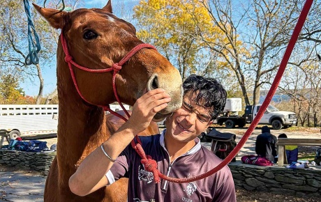 Image of a horse sniffing a student's head.