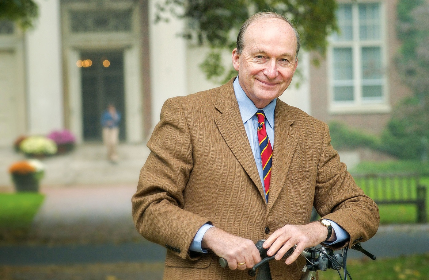Image of Eric Widmer in a suit and tie smiling in front of a campus building